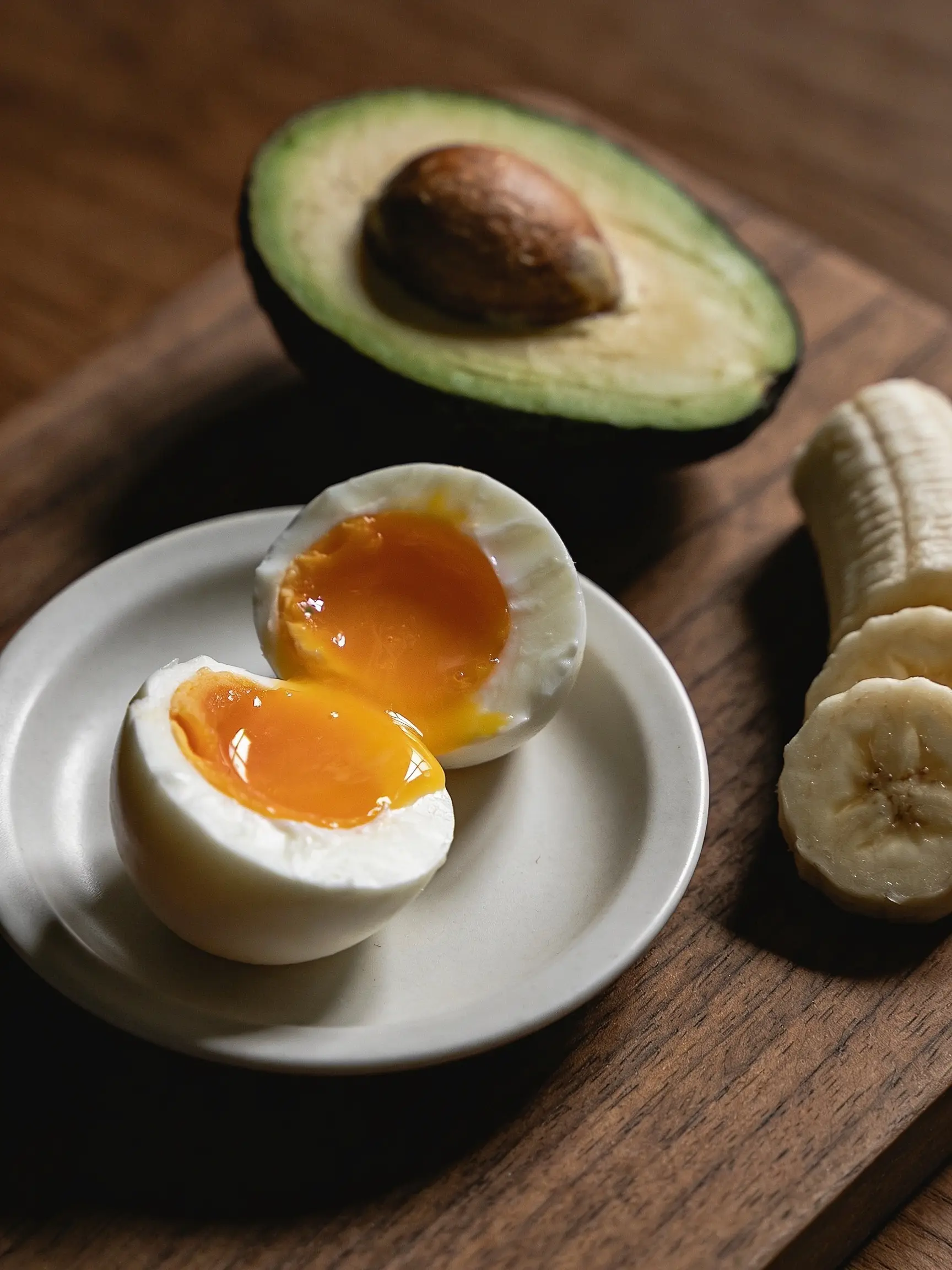 Soft boiled egg with jammy yolk alongside avocado and banana